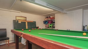 A pool table with balls, a chair, and a shelf with toys. - Meltham Guest House (Scarborough)