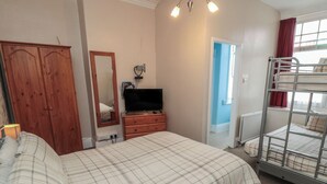 A bedroom with a bed, a dresser, a television, a wardrobe, and a bunk bed. - Meltham Guest House (Scarborough)