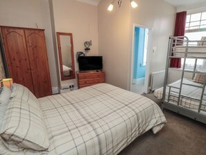 A bedroom with a bed, a dresser, a television, a wardrobe, and a bunk bed. - Meltham Guest House (Scarborough)
