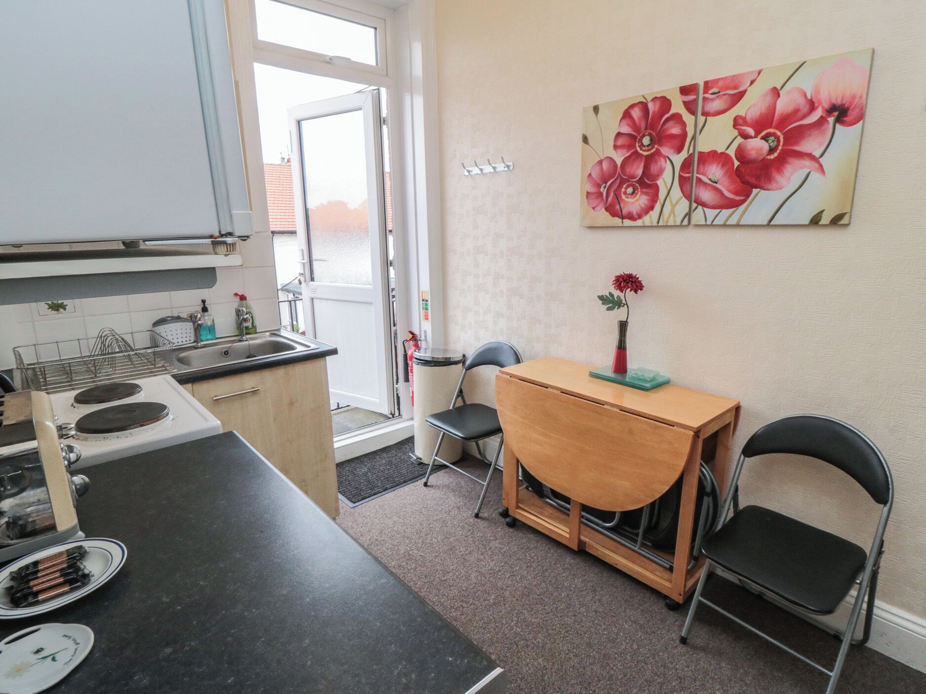 A compact kitchen with a stove, sink, and a dining area with chairs and a table.