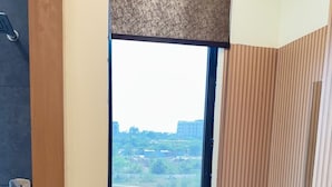 A bathroom with a large window, wooden paneling, and a marble floor. - Hotel Shri Radhavan (Mathura)