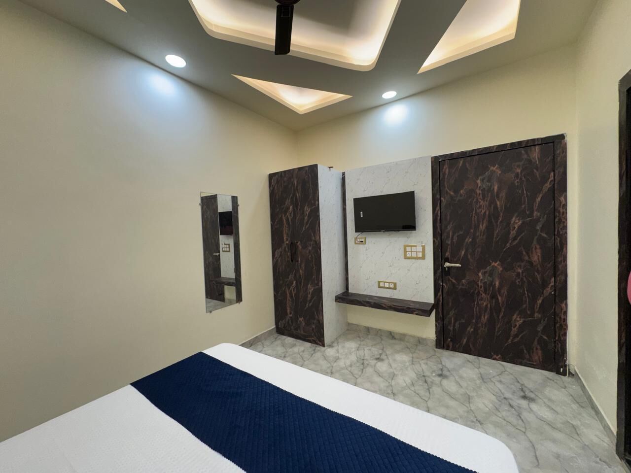 Un dormitorio con cama, televisor en la pared y armario.