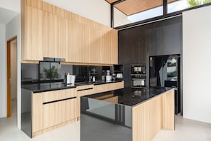 Eine moderne Küche mit Holzschränken, schwarzen Arbeitsplatten und einer großen Kochinsel.