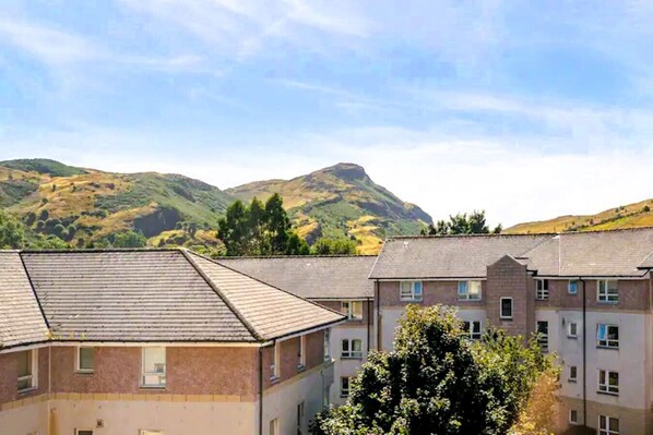 A residential area with multiple two-story houses, a clear sky, and a mountain in the background. - Vrbo Property (Edinburgh)