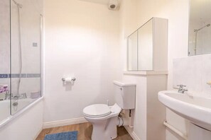 A bathroom with a toilet, a sink, a shower, and a mirror. - Vrbo Property (Edinburgh)