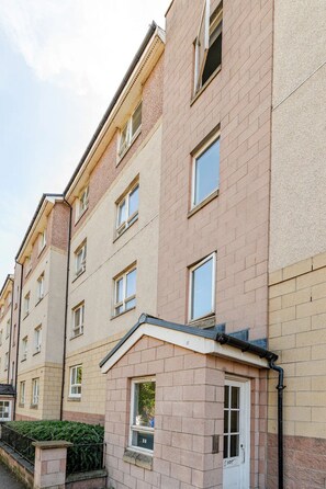 A multi-story residential building with a brick facade, multiple windows, and a visible door with a number. - Vrbo Property (Edinburgh)