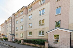 En flervåningsbostadsbyggnad med en enhetlig fasad, många fönster och en liten trädgård framför.