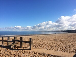 A sandy beach with a wooden fence, a clear sky, and distant hills. - Vrbo Property (Edinburgh)