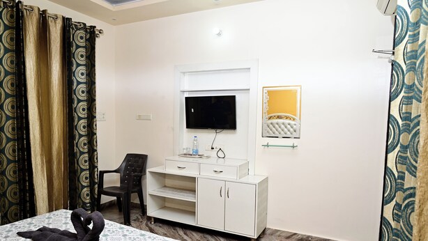 Una habitación de hotel con cama, televisión, mueble pequeño y silla.