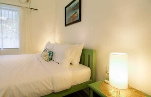 A bed with white bedding, a green headboard, a bedside lamp, and a painting on the wall. - $ 4 Homestay in Amritsar (Amritsar Cantt.)