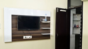 Un televisor montado en la pared, una botella de agua y un dispensador de jabón sobre una repisa.