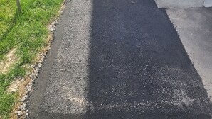 A paved pathway leading to a building with a stone wall and an air conditioning unit. - Cozy 2-bedroom Basement Unit Near Calypso Water Park Embrun (Embrun)