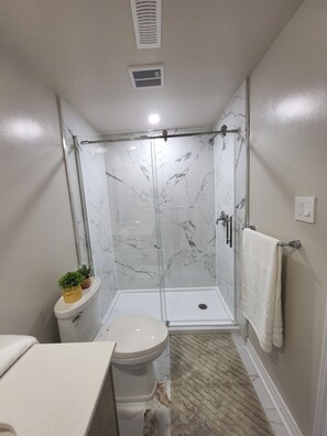 Uma casa de banho moderna com cabine de duche em vidro, sanita e lavatório.