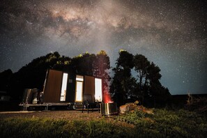 Una piccola baita con un cielo stellato sopra, un braciere e un serbatoio d'acqua portatile.