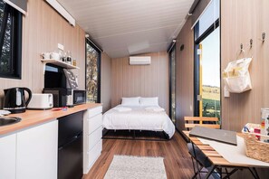 Una stanza compatta con un letto, angolo cottura e vista sull'esterno.