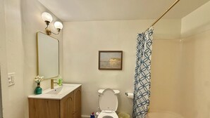 Un baño con inodoro, lavabo, espejo y cortina de ducha.