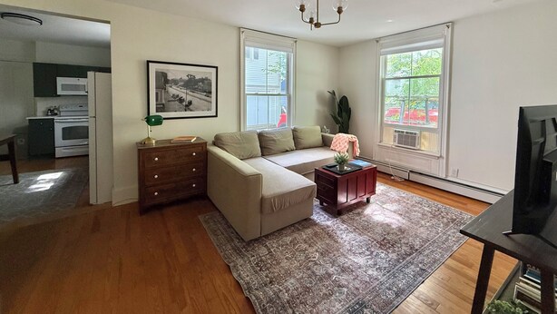 Una sala de estar con sofá, una mesa de centro, televisión, chimenea y una zona de cocina.