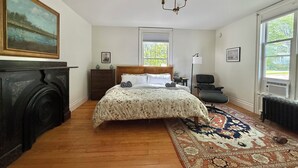 Un dormitorio con cama, chimenea, ventana y candelabro.