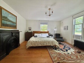 Une chambre à coucher avec un lit, une cheminée, une fenêtre et un lustre.