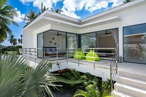 A modern house with a balcony, large windows, and tropical plants. - Villa Mona | Stylish 3BR Pool Villa (Bo Put)