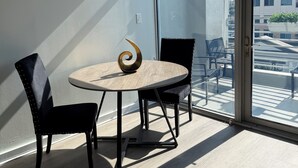 A modern room with a round table, two chairs, and a view of a balcony with outdoor furniture.