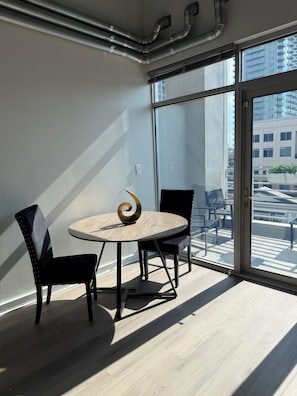 Habitación moderna con una mesa redonda, dos sillas y vistas a un balcón con mobiliario exterior.
