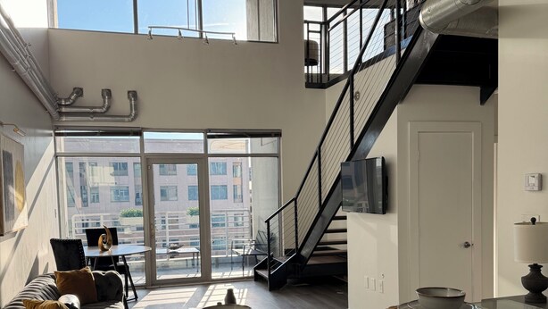 A modern kitchen with a glass dining table, stainless steel appliances, and a view to the outside.