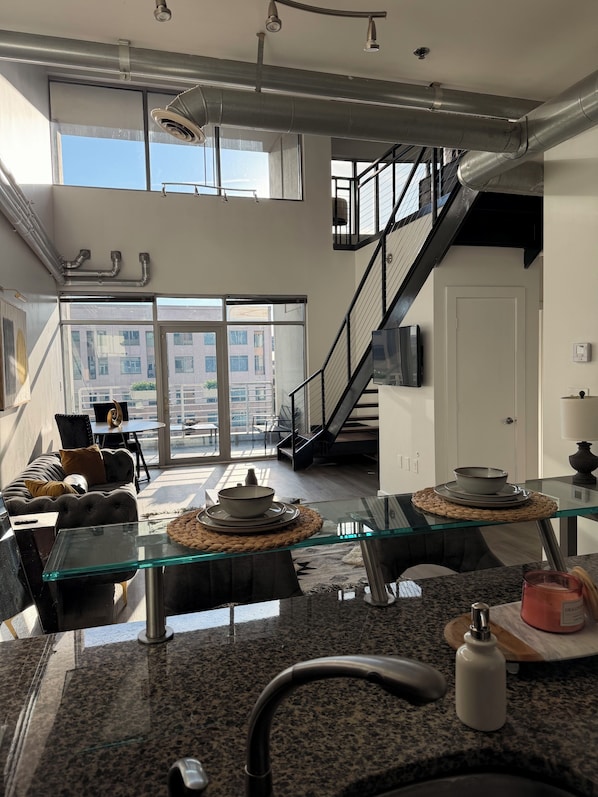 Una cocina moderna con una mesa de comedor de vidrio, electrodomésticos de acero inoxidable y vistas al exterior.