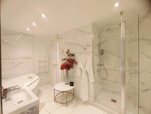 Un baño moderno con ducha envuelta en vidrio, un lavamanos blanco y piso de baldosas de m ármol.