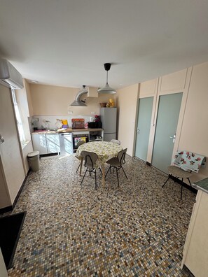 A compact kitchen with a tiled floor, a dining table with chairs, a refrigerator, and a sink. - Vrbo Property (Valençay)