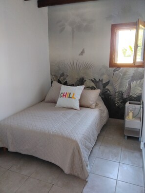 A bedroom with a bed, a nightstand, a wall mural, and a window.