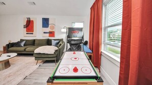 Ett vardagsrum med ett shuffleboard-bord, en soffa, ett soffbord och en basketkorg.