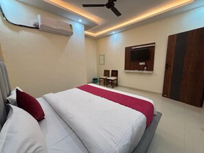 A bedroom with a bed, a ceiling fan, an air conditioning unit, a television, and a door. - Hotel Rising Banquet and Restaurant (Faizabad)
