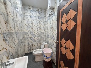 Et badeværelse med toilet, håndvask og en dekorativ dør.