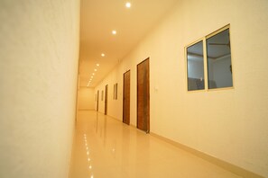 Un pasillo con puertas y ventanas, piso pulido e iluminación empotrada.
