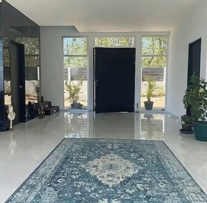 A modern interior with a reflective floor, a patterned rug, and potted plants. - Vrbo Property (Puerto Carrillo)