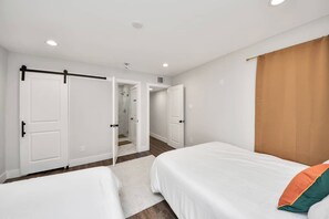 A bedroom with two beds, a shower, and a door leading to another room. - Modern Retreat l Sleeps 20+ l w/Loft Lounge (Houston)