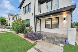 A modern two-story house with a stone entryway, a well-maintained lawn, and a clear sky. - Modern Retreat l Sleeps 20+ l w/Loft Lounge (Houston)