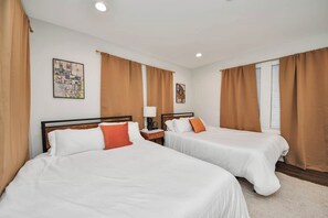 Ein Hotelzimmer mit zwei Betten, einem Nachttisch, einer Lampe und Bildern an den Wänden.