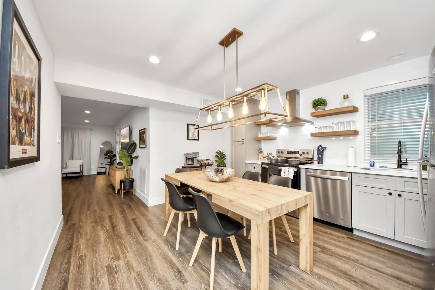Una cocina moderna con una mesa de comedor de madera, sillas negras y una lámpara colgante.