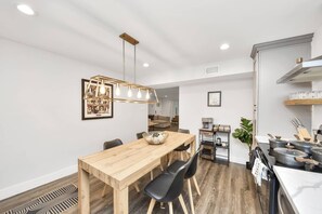 Eine moderne Küche mit Holztisch, schwarzen Stühlen und einer Pendelleuchte.