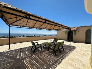 A covered outdoor seating area with a view of the sea, a table, and chairs. - Grotte de Sel Private Pool (Ghar El Melh)