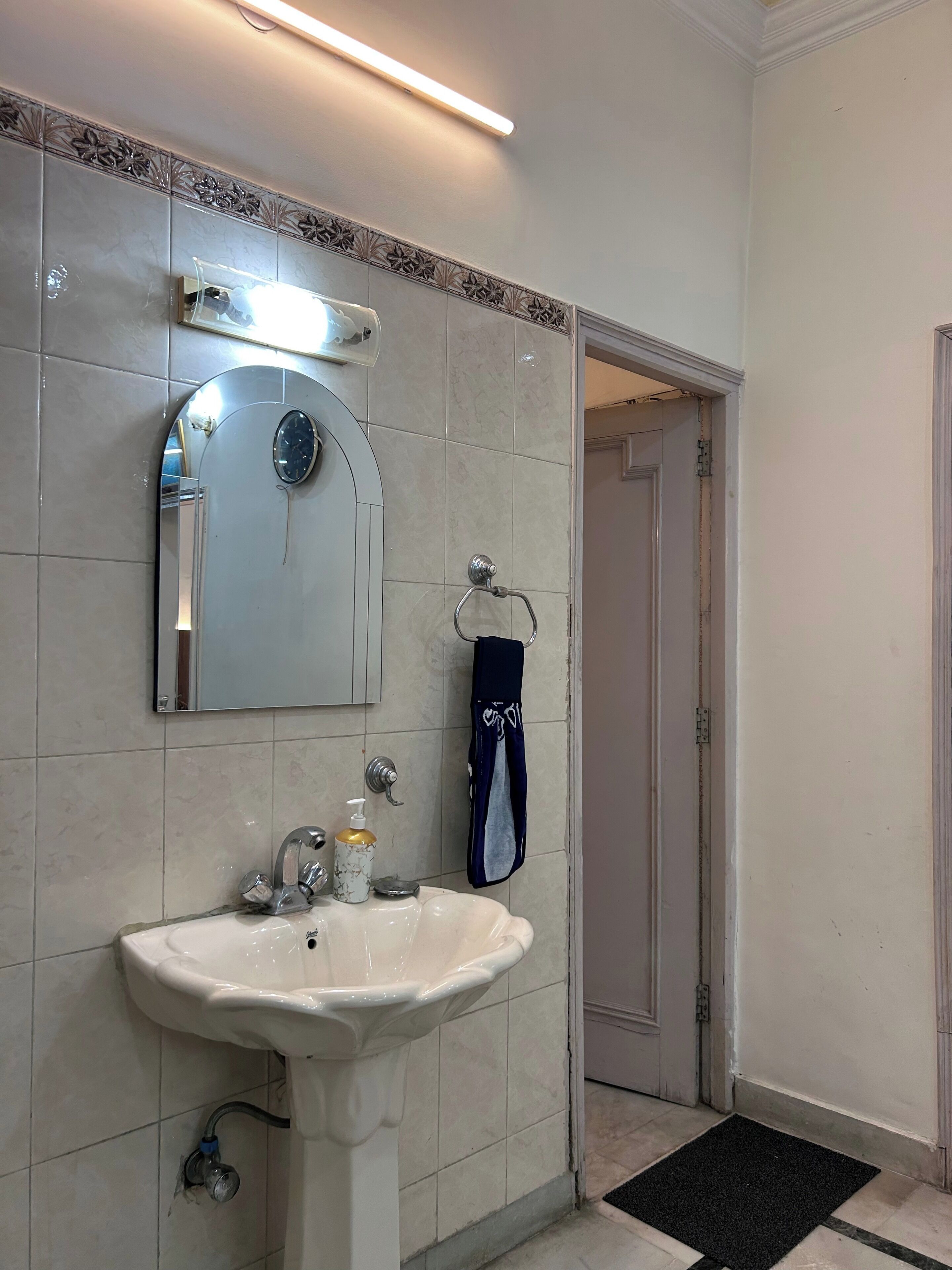 A bathroom with a white sink, a mirror, and a towel rack.