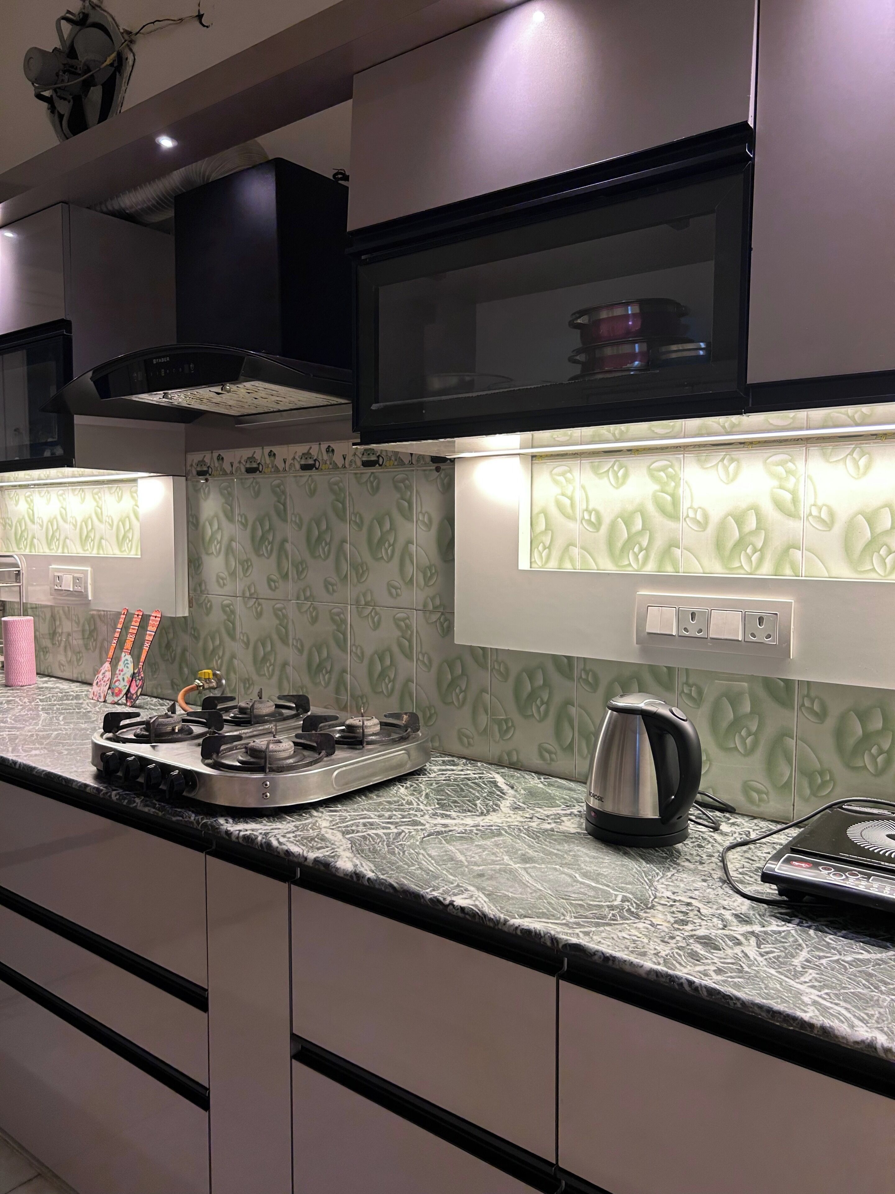 A kitchen with a gas stove, kettle, and microwave.