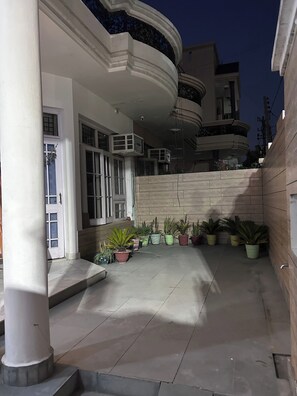 A building with a curved balcony, a stone wall, and potted plants. - Charming Bungalow Rental in Jammu (Jammu)