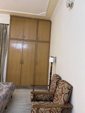 A room with a wooden wardrobe, a patterned sofa, and a lamp. - Charming Bungalow Rental in Jammu (Jammu)