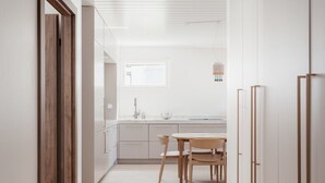 A modern kitchen with a dining area, wooden flooring, and white cabinetry. - Premium 3BR Home | Prime Location | Modern Touch (Helsinki)