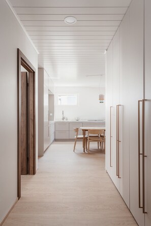 Eine moderne Küche mit Essbereich, Holzboden und weißen Schränken.