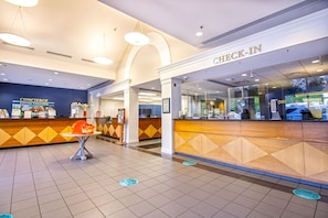 Eine Hotelhalle mit Rezeption, Concierge-Schalter und einer Sitzecke.