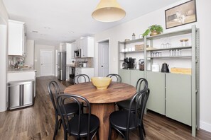 Une cuisine moderne avec une table à manger en bois, des chaises noires et un luminaire suspendu.